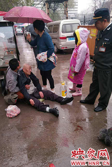 女孩為倒地老人撐傘。