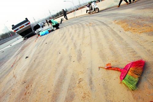 被撞的環(huán)衛(wèi)工躺在地上，身上蓋著藍(lán)色布塊，現(xiàn)場除散落的汽車碎片外，還留有被撞斷的掃帚。