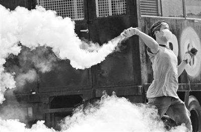 12月2日，泰國曼谷，一名反政府示威者在總理府附近向負責執(zhí)勤的警察投擲催淚彈。英拉請求示威者不要再試圖占領政府工作部門，不要逼迫政府工作人員選邊站。