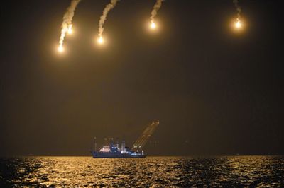 22日，搜救人員在照明彈的光亮下連夜搜救。