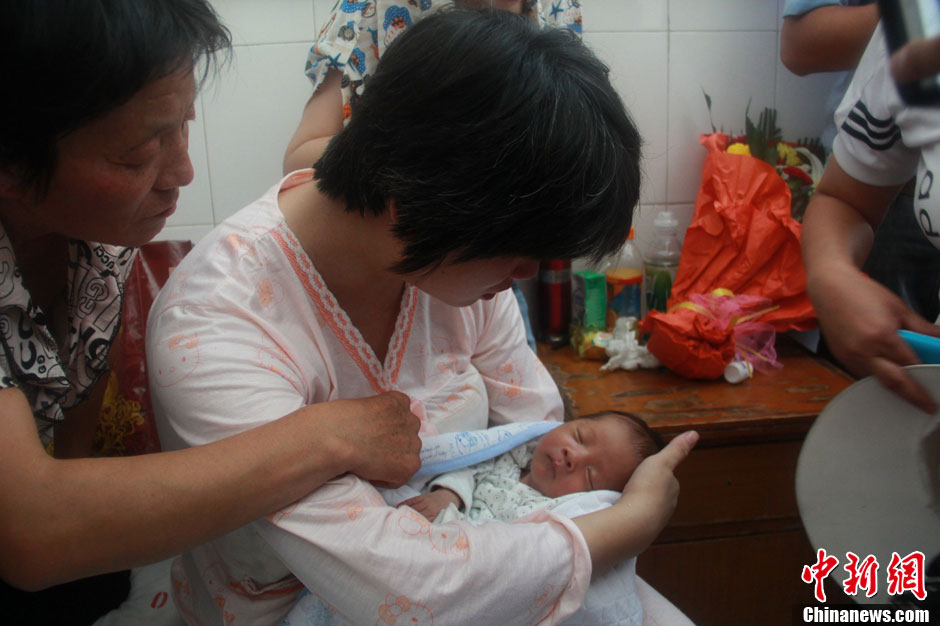 圖為久別重逢，獲救嬰兒母親悉心撫摸愛(ài)子。張一辰 攝