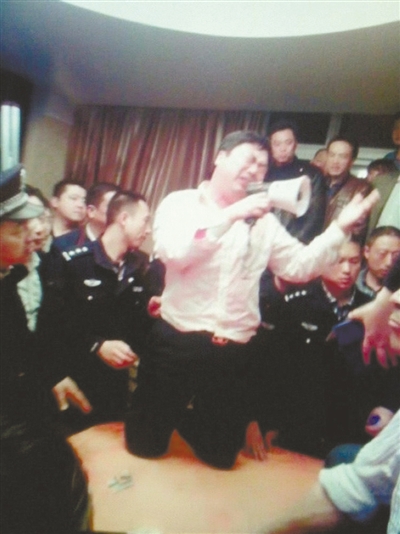 　4月19日，泰州市濱江工業(yè)園區(qū)管委會招待中心，一男子跪在酒桌上喊話求饒。李根 攝