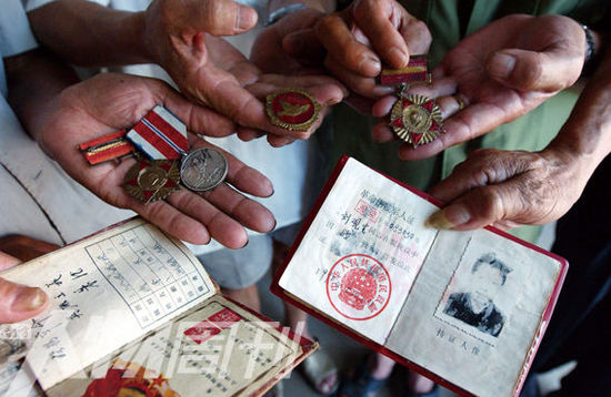 幾位志愿軍老兵展示自己的立功證、傷殘軍人證與勛章