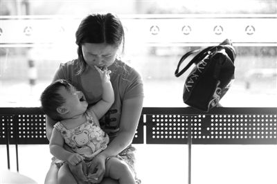 昨日，肯德基京廣中心店門口，姜女士提起跟養(yǎng)父母的關(guān)系時落淚，懷中9個月的女兒笑著跟她玩。新京報記者 薛珺 攝