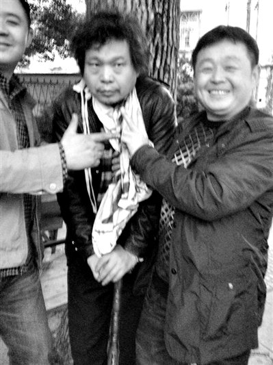 兩名接訪人員與患有癌癥的訪民段新德合影時(shí)，面帶笑容擺出勝利的手勢。