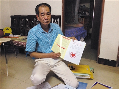 翻出一家網(wǎng)站贈(zèng)予的“中國(guó)好人”證書，區(qū)少坤單膝跪在地上，“你看，我是中國(guó)好人啊?！?范春旭 攝