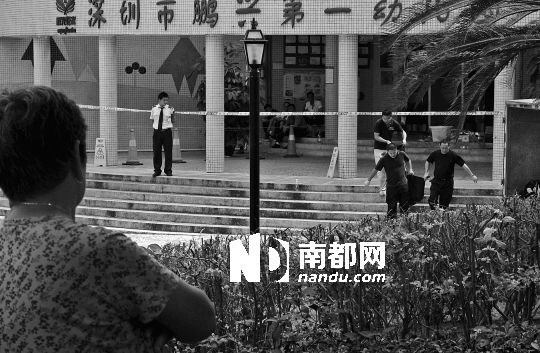 →7月19日，鵬興花園第一幼兒園門前，民警在現(xiàn)場進行完勘查取證后，園長和保安的尸體被運走。南都記者 徐文閣 攝