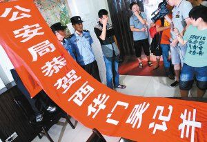 面對(duì)警方收繳的條幅，老板楊某也不好意思地用手遮擋臉