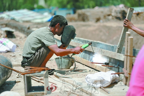 　正午陽光下，工地上的焊接工人還在認真工作。