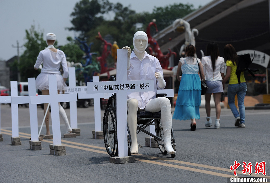 4月16日，重慶市洋人街上擺放著兩個(gè)受了傷的塑料人像“模特”，旁邊十字架上寫著向“中國式過馬路”說不