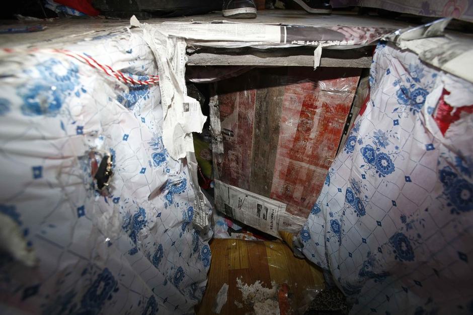 陳小龍?jiān)诔鲎馕萃?，自行又圍起一堵圍墻，安裝了一個(gè)門。圍墻上都是豎起的鐵釘，外面堆著土，鄰居猜是從地底挖出來(lái)的。洞口就在床邊，0.5米見(jiàn)方，深約1.5米。洞口表面一塊紙板掩蓋，打開紙板跳入洞底，是一扇小木門，木門外有插銷，可以從外面鎖上。