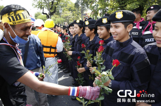 2013年12月03日,曼谷總理府與曼谷警署允許反政府示威民眾進(jìn)入,雙方進(jìn)入暫時(shí)“停戰(zhàn)”狀態(tài)迎接泰王生日。曼谷警察總署,女警們手持鮮花送給反政府示威民眾。圖片來源:Manish Swarup/東方IC