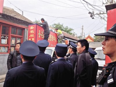 昨日下午,東城區(qū)工商、城管、公安等部門,對(duì)雍和宮附近的預(yù)測(cè)中心進(jìn)行清理整頓,站在車頂?shù)膬擅と苏鸪患摇邦A(yù)測(cè)中心”的招牌。因雍和宮、白云觀等文化景點(diǎn)外聚集大量算命先生,被媒體稱為“算命一條街”。本版攝影/新京報(bào)記者 李寧 攝