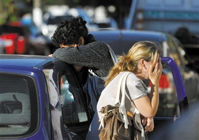 27日，遇難者親友在火災(zāi)現(xiàn)場旁哭泣。