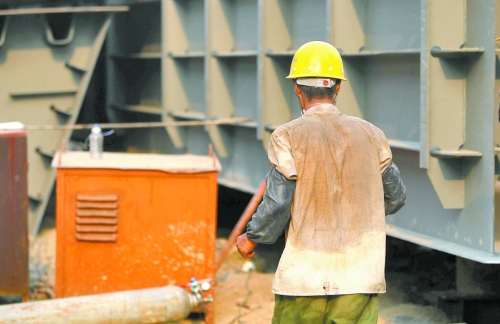 工地上，一建筑工人的衣服被汗水浸透。