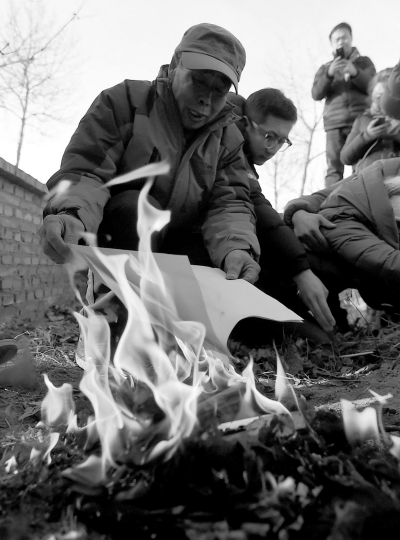 李三仁在兒子墳前焚燒再審無罪判決文書的復印件。新華社發(fā)