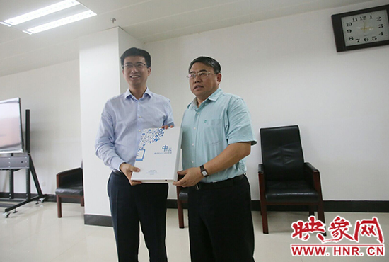 阿里云計(jì)算總裁胡曉明向河南省新聞出版廣電局局長朱夏炎遞交《中原云平臺交付手冊》。