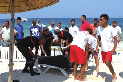 6月26日，在突尼斯蘇塞，救生員和醫(yī)務(wù)人員在發(fā)生襲擊事件的海灘運(yùn)送一名死者的遺體。新華社發(fā)