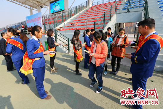 活動現場工作人員給同學們發(fā)放宣傳冊、環(huán)保袋。