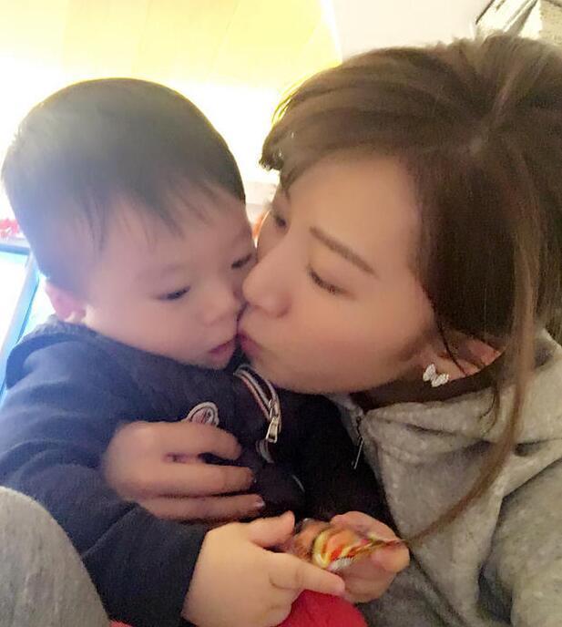 照片中李念狂吻兒子，小寶貝自顧自地玩著。