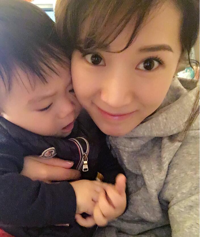 照片中李念狂吻兒子，小寶貝自顧自地玩著。