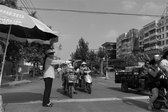 昨日，開(kāi)封市區(qū)一名協(xié)管員在指揮群眾過(guò)馬路