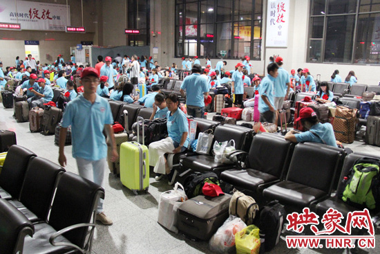 大學(xué)生志愿者在火車站候車室內(nèi)整裝待發(fā)。