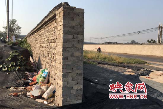 一墻之隔，一邊是道路，一邊是垃圾和荒草，市民質(zhì)疑其為遮羞墻。