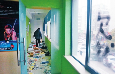 　健身會(huì)所地上一片狼藉，玻璃上噴著黑色“欠錢”二字。