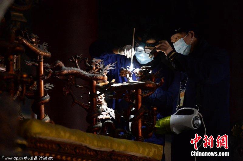 圖為工作人員使用軟毛刷和吸塵器對太和殿的金漆雕龍寶座除塵。