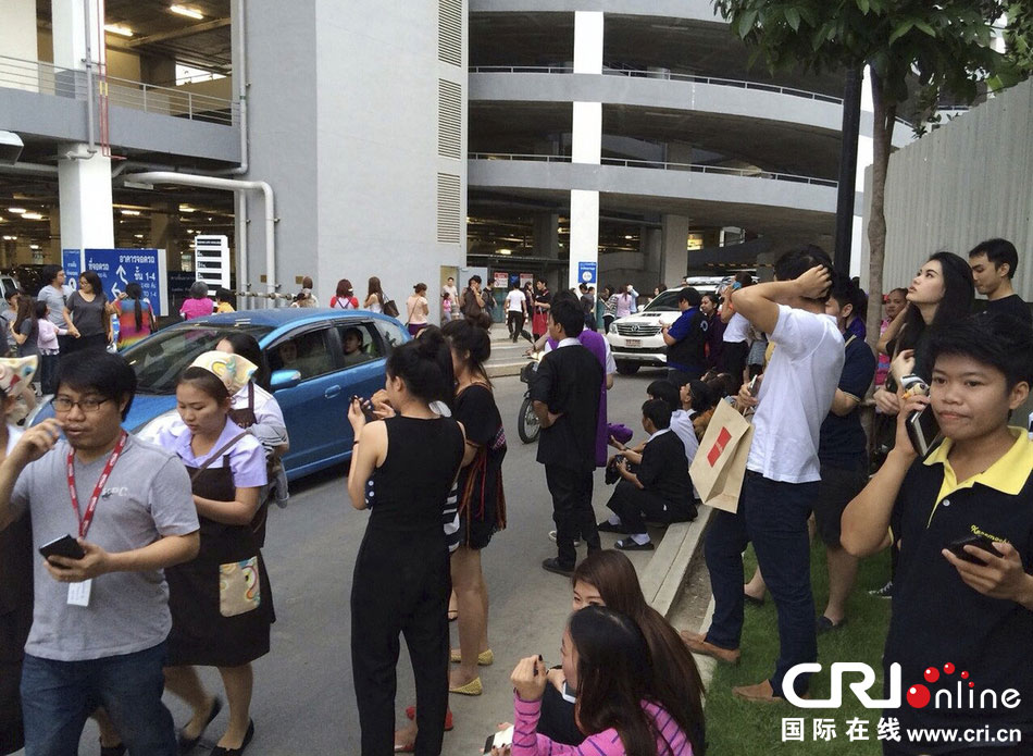 當(dāng)?shù)貢r間2014年5月5日，泰國清萊，工人們站在一棟大樓外避難。