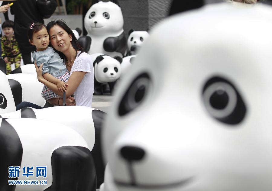 6月2日，一位家長(zhǎng)帶著孩子在上海街頭和大熊貓模型合影。