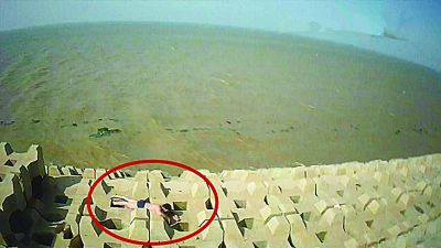 孫正龍游上岸，趴在海邊精疲力盡。