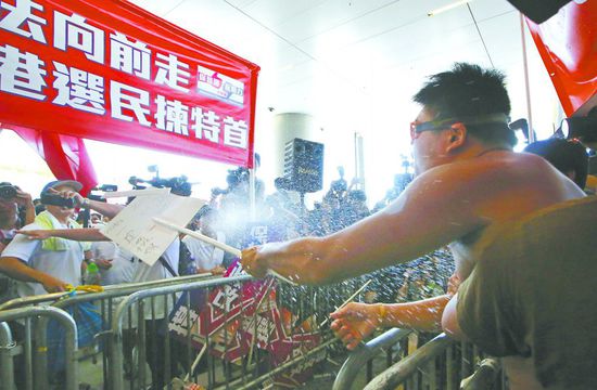 17日，在香港立法會外，一名反對政改的男子向支持派人群投擲標(biāo)牌。
