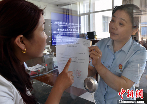 資料圖：2015年5月4日，河北石家莊市橋西區(qū)人民法院立案庭庭長齊燕正在為立案人辦理相關手續(xù)，完成整個過程只用了5分鐘。當日是立案登記制改革首個工作日，該院共立案36件，立案率達到90%。中新社發(fā) 翟羽佳 攝