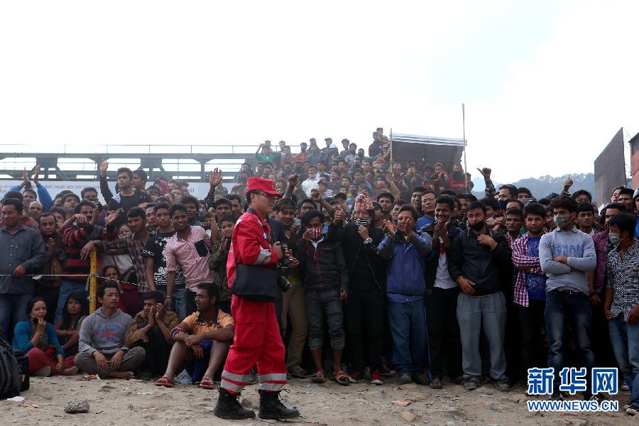 圍觀的尼泊爾民眾在中國國際救援隊(duì)成功搜救出幸存者后向搜救隊(duì)員歡呼致意。