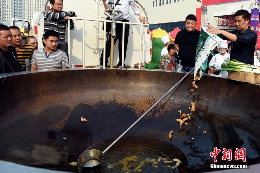 工作人員向大鍋內(nèi)加入油和姜等烹飪調(diào)料。 圖片來(lái)源：CFP視覺中國(guó)