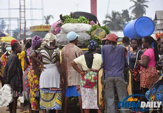 當(dāng)?shù)貢r間2014年8月14日，利比里亞蒙羅維亞，市場里的商人們圍著一輛汽車。