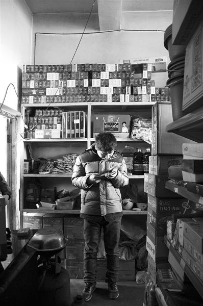 1月21日，周瑋在自家的超市里玩計(jì)算器。